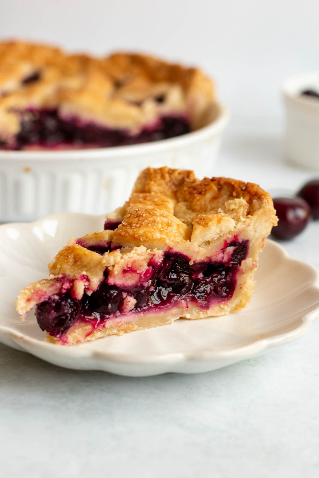 Slice of cherry pie on a white plate.