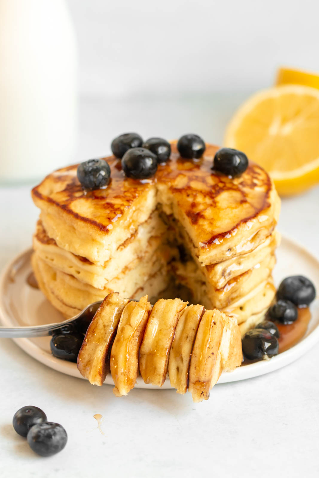 Stack of lemon ricotta pancakes with a bite missing.