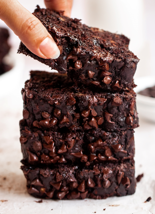 Hand lifting a slice of double chocolate banana bread.