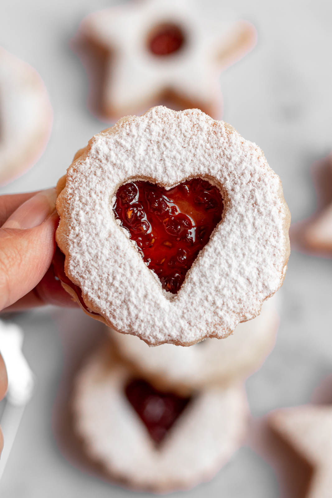 Hand holding a linzer cookie.