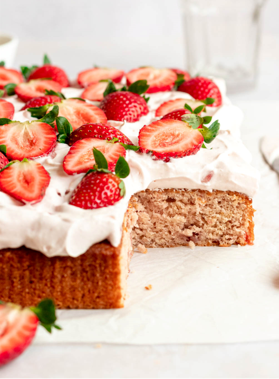 Fresh strawberry sheet cake on a parchment paper.