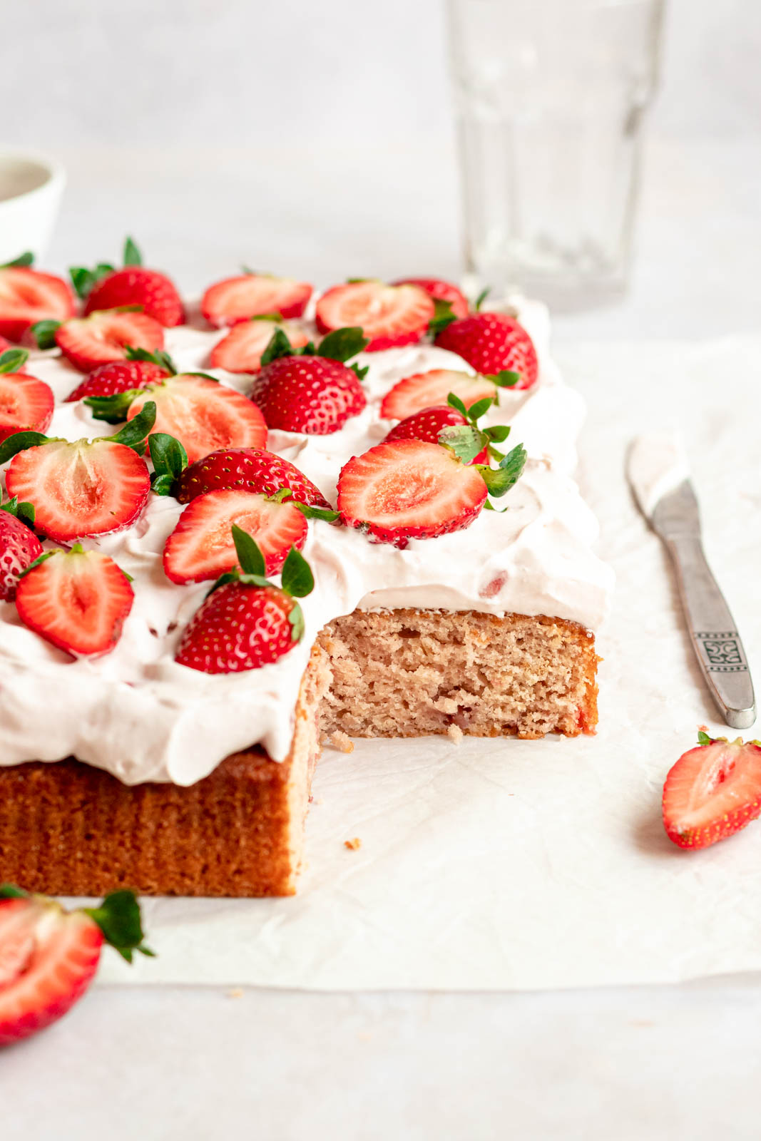 Fresh strawberry sheet cake on a parchment paper.