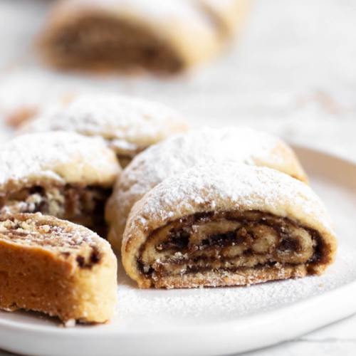 Rolled date cookies on a white plate.
