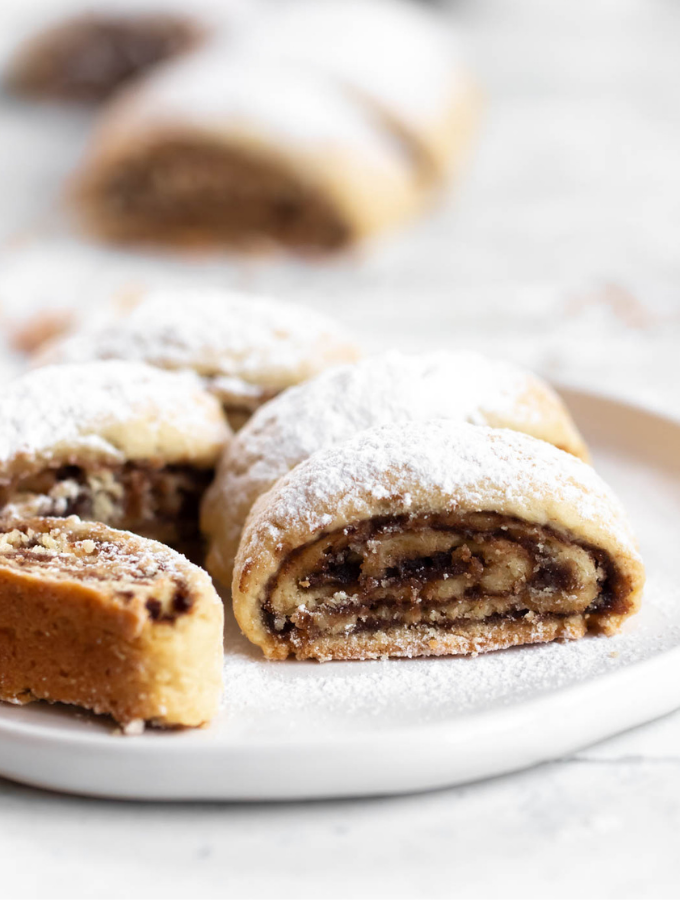 Rolled date cookies on a white plate.