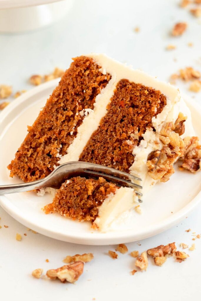 Slice of carrot cake with a fork inserted into the cake.