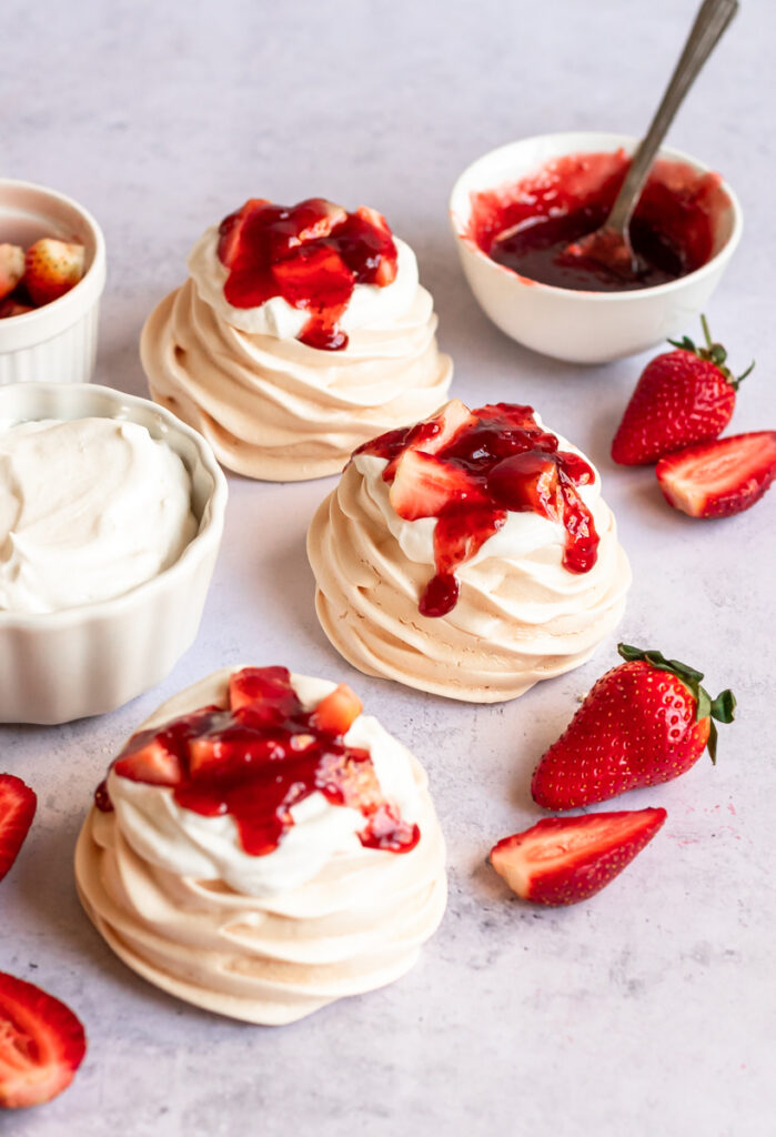 mini strawberry pavlova with fresh strawberries, whipped cream, and strawberry sauce