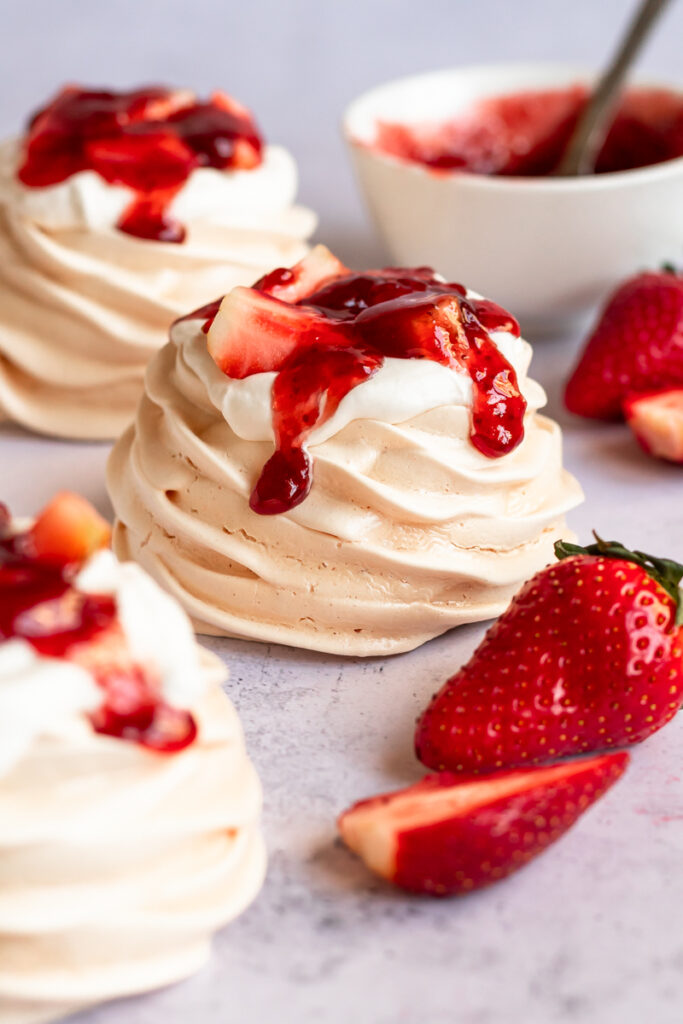 mini pavlova nests with strawberries on top with whipped cream