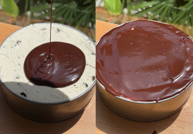 Smooth, glossy chocolate ganache is being poured and spread over the top cream layer of the cheesecake.