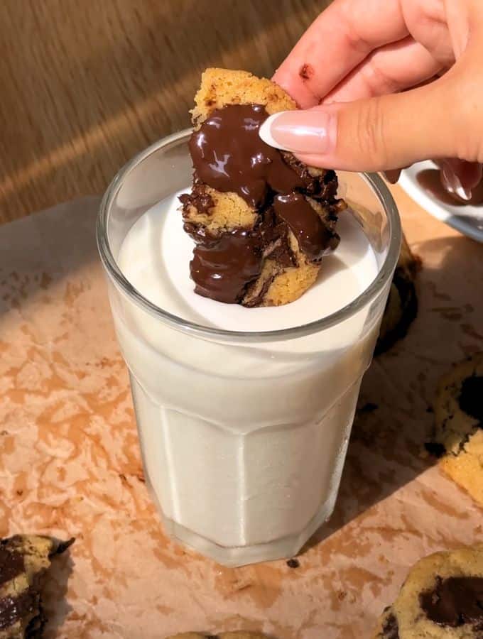 Piece of small batch chocolate chip cookie dipped in cold milk.