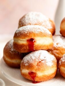 Stack of sufganiyot filled with strawberry jelly.