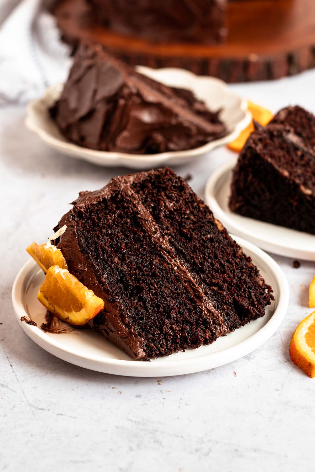 3 slices of chocolate cake on white plates next to each other.