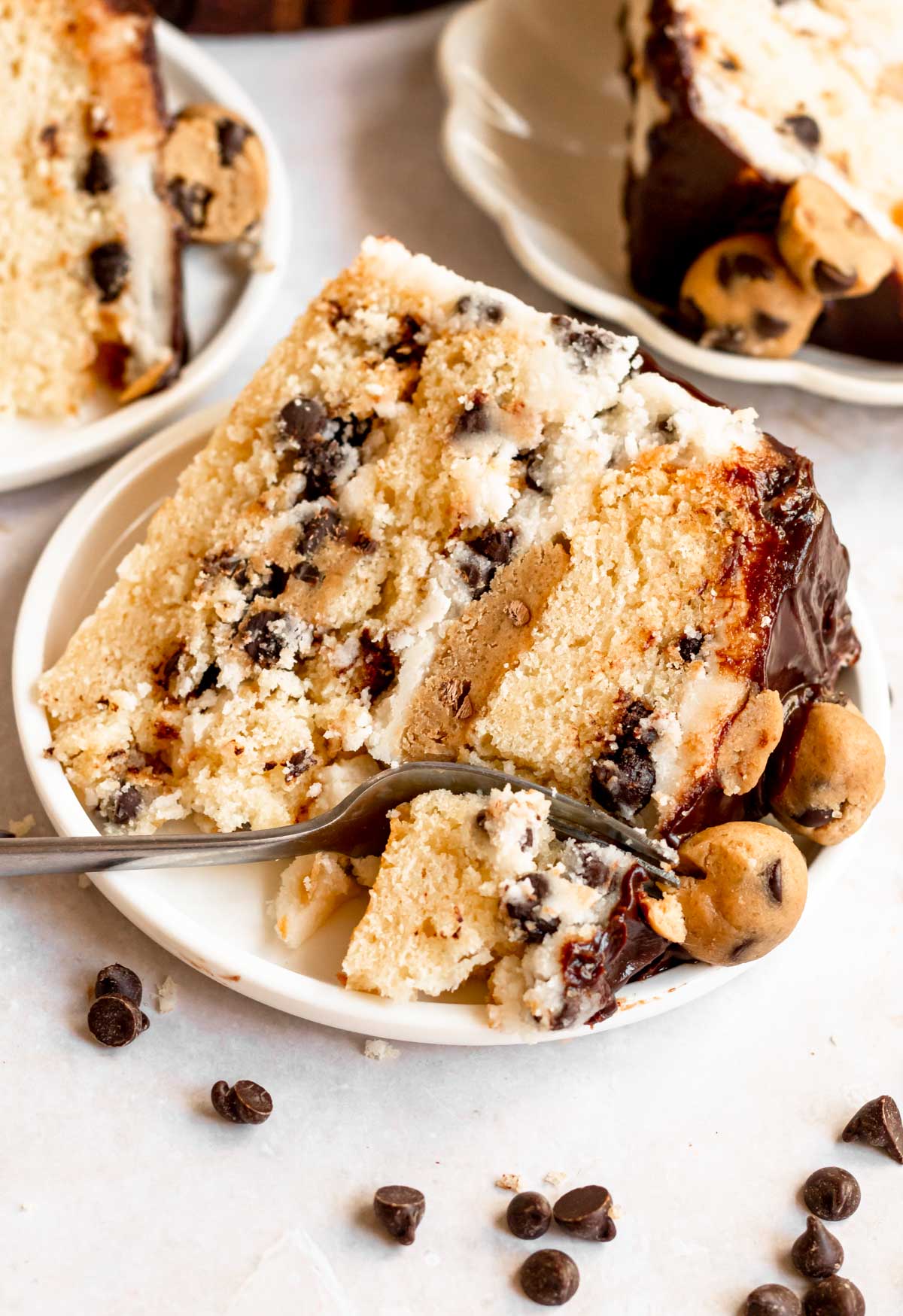 Slice of cookie dough cake on a white plate with a fork inserted into the cake.