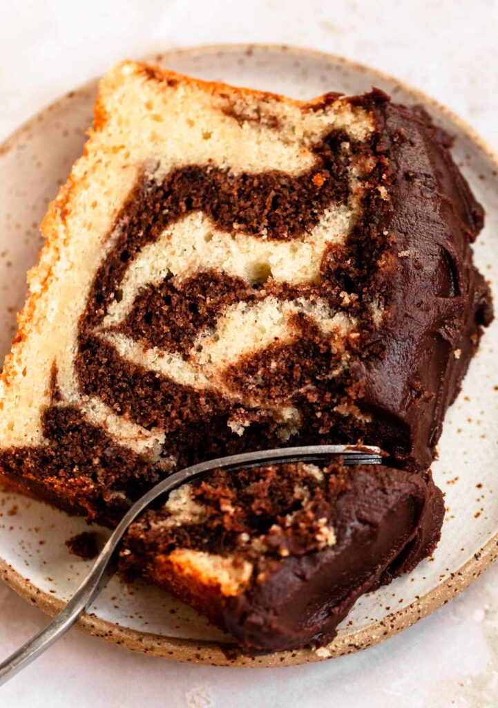 Slice of loaf cake on a plate with a fork inserted into the cake.