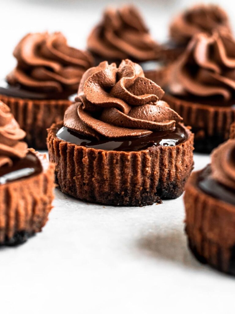 Mini chocolate cheesecakes with chocolate whipped cream on top.