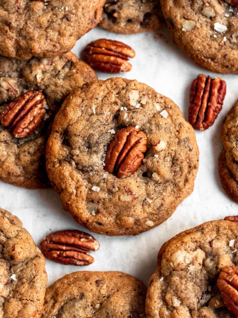 Brown butter pecan cookies with pecans around it on a white backround.