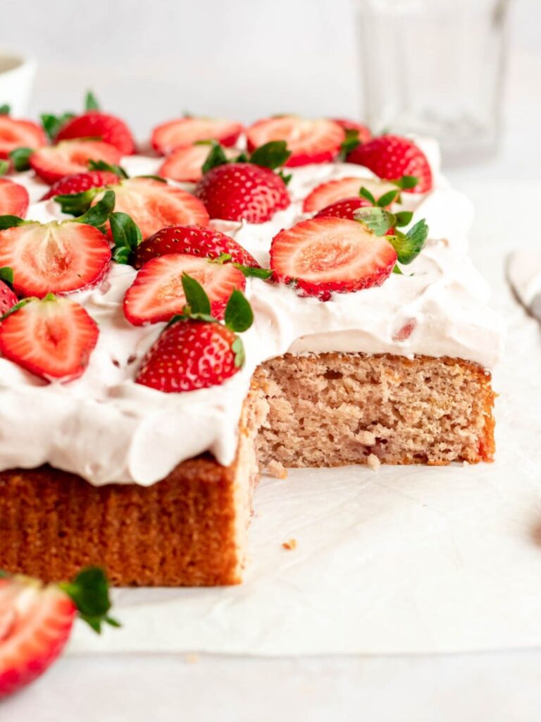 Slice missing from strawberry sheet cake.