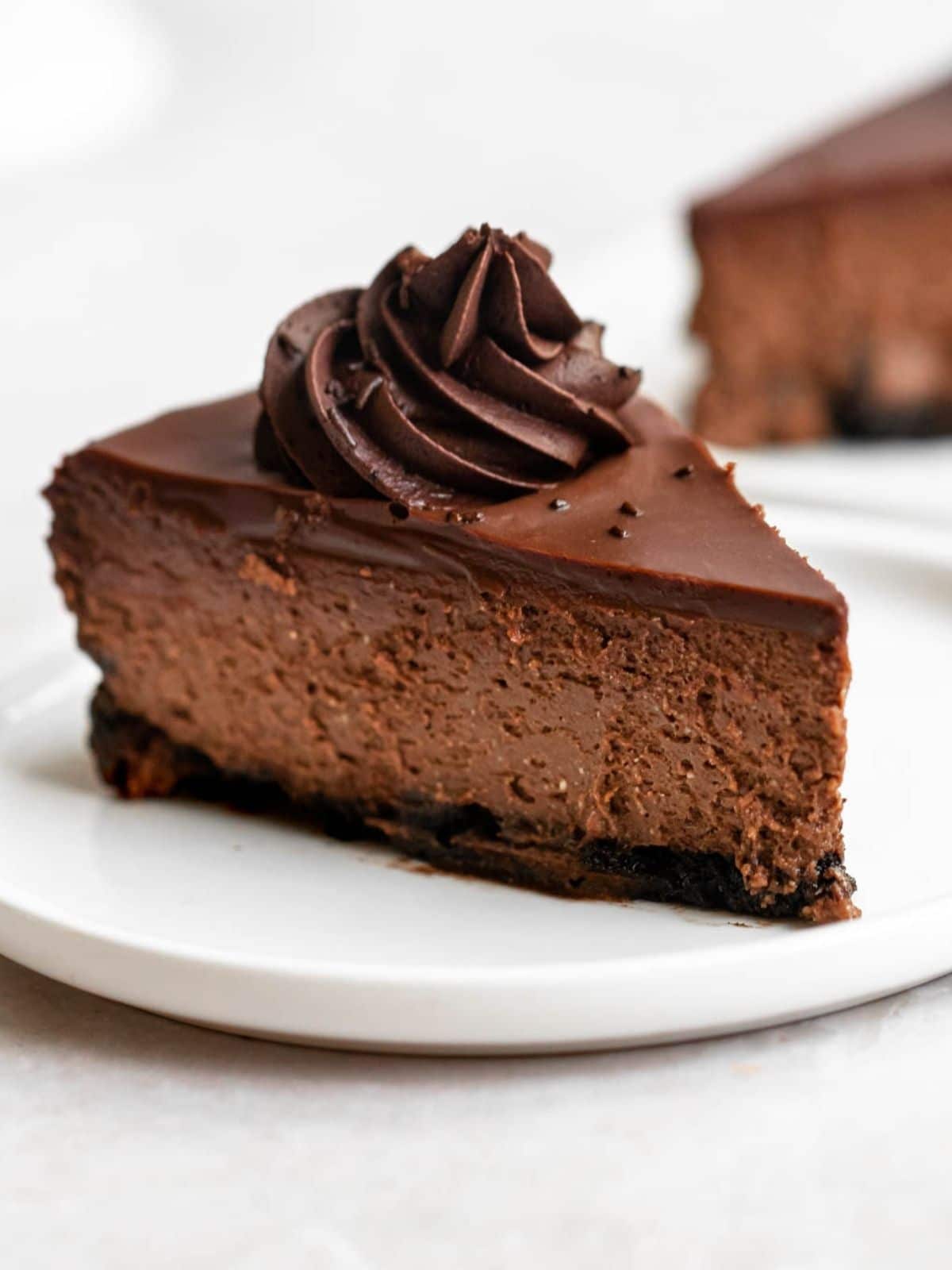 Slice of triple chocolate cheesecake on a white plate.