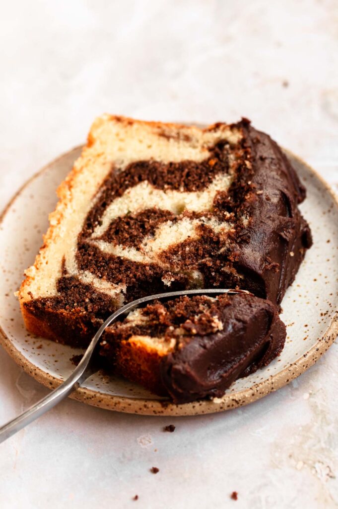 Slice of marble loaf cake on a dessert plate with a fork in it.