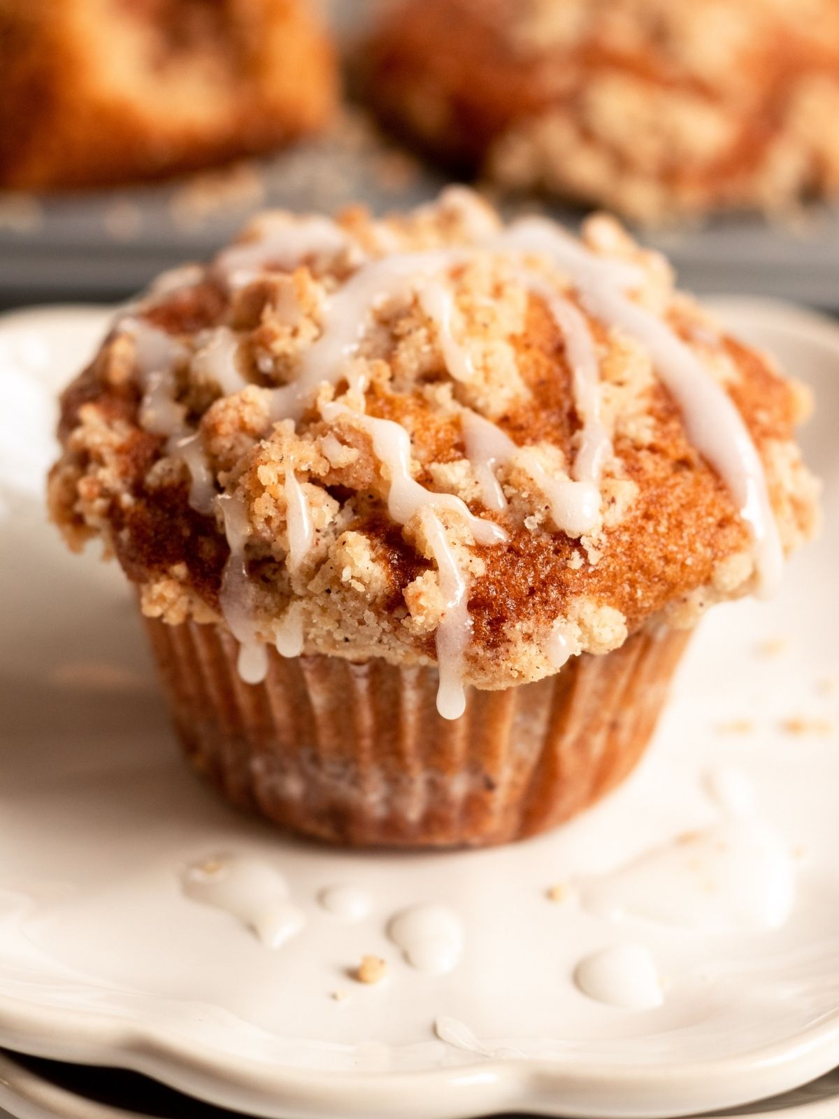 Coffee cake muffin on a small plate with glaze on top.