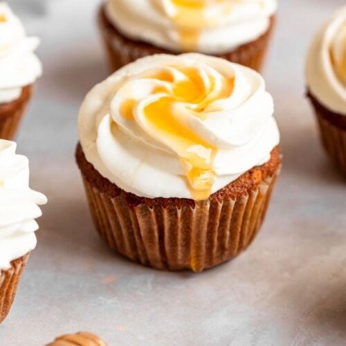 Honey cupcakes with whipped cream and honey on top.