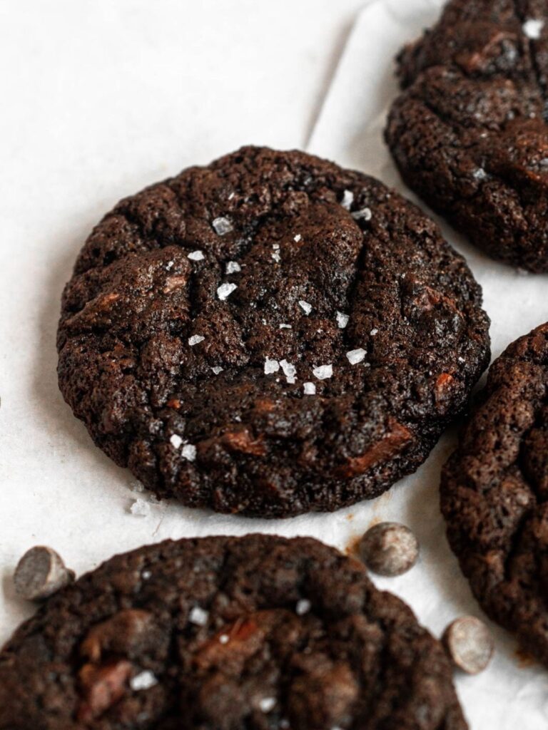 double chocolate cookies next to each other on a white backround with chocolate chips on the side.