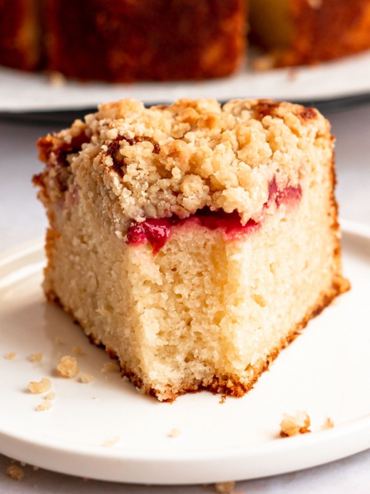 Bite missing from a slice of strawberry crumble cake.