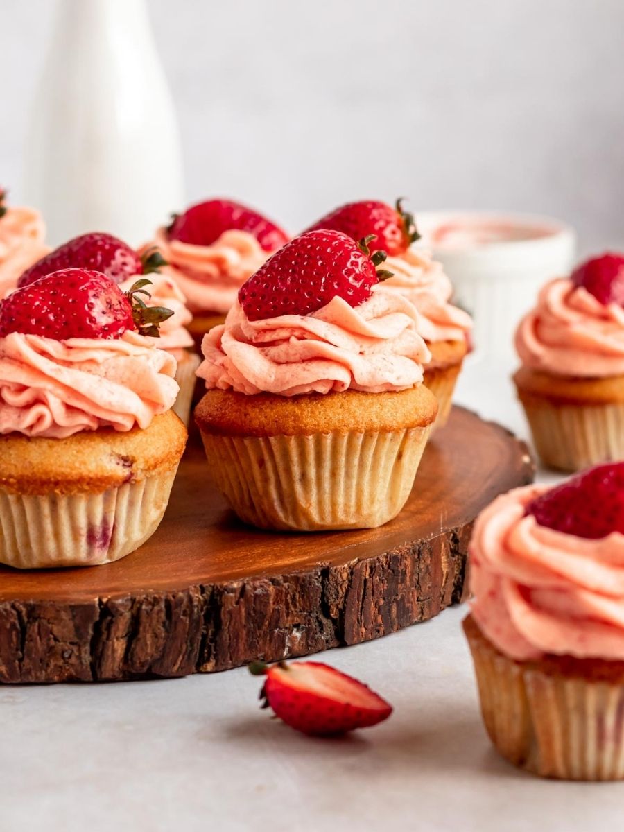 Strawberry filled cupcakes on a wooden platter.