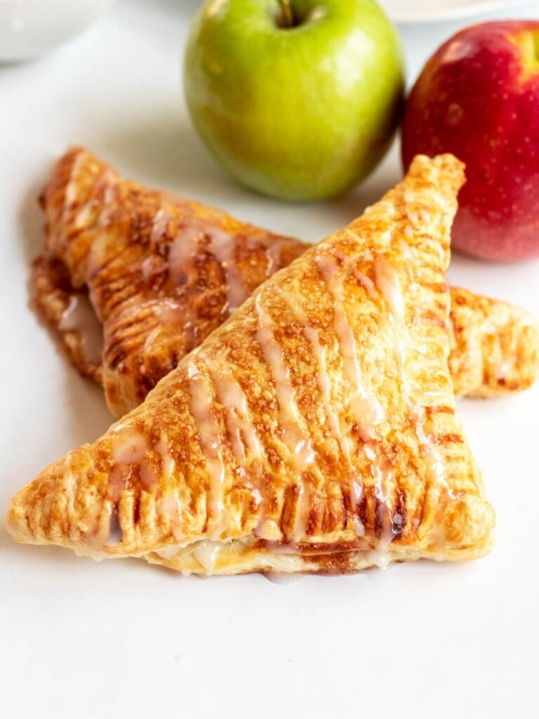 Two apple turnovers with apples on the side.
