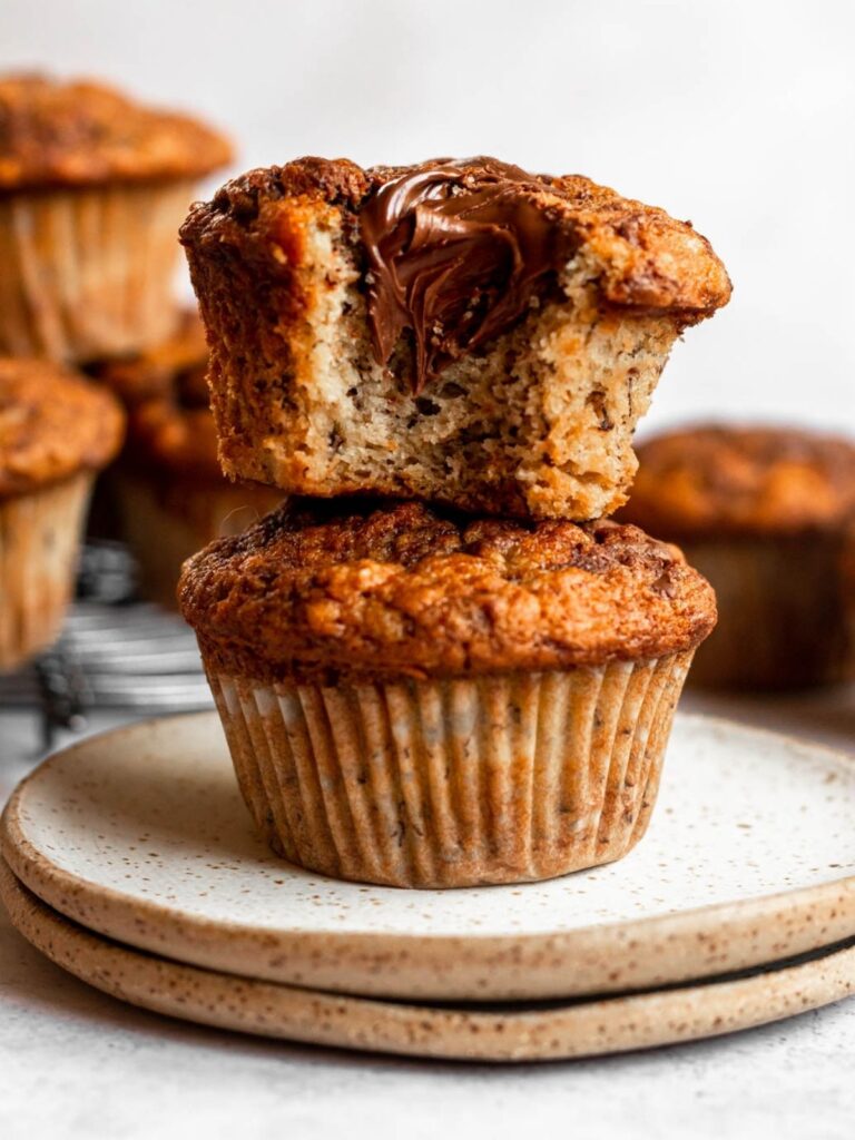 Stack of two muffins with a bite missing from the top muffin.
