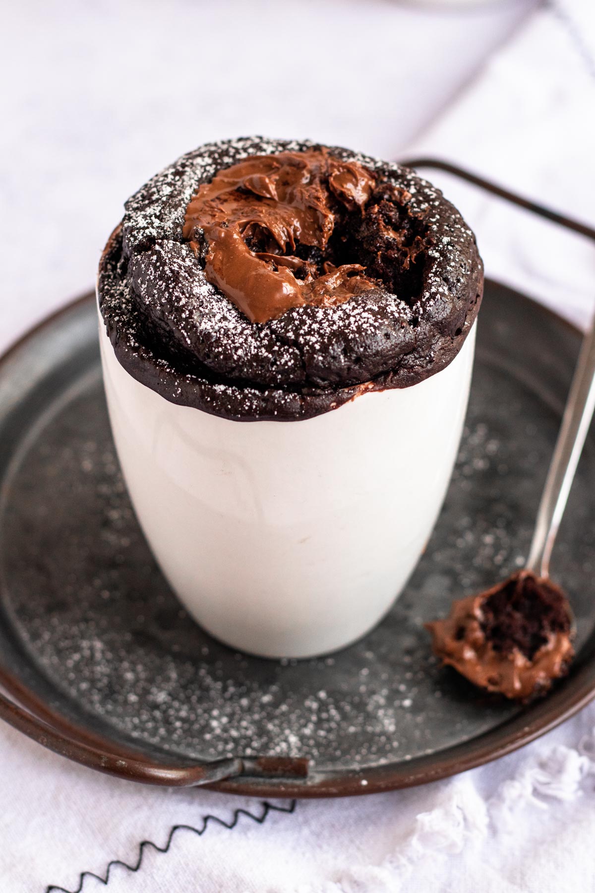 Nutella mug cake on a plate with a bite missing.