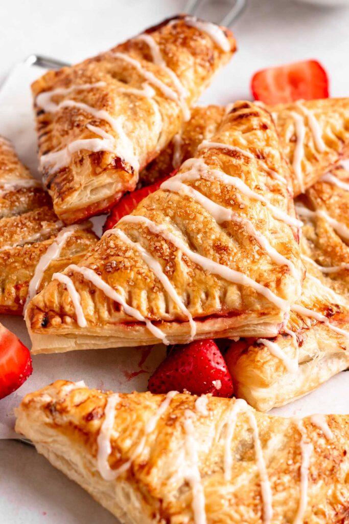 Pile of strawberry turnovers with glaze on top.