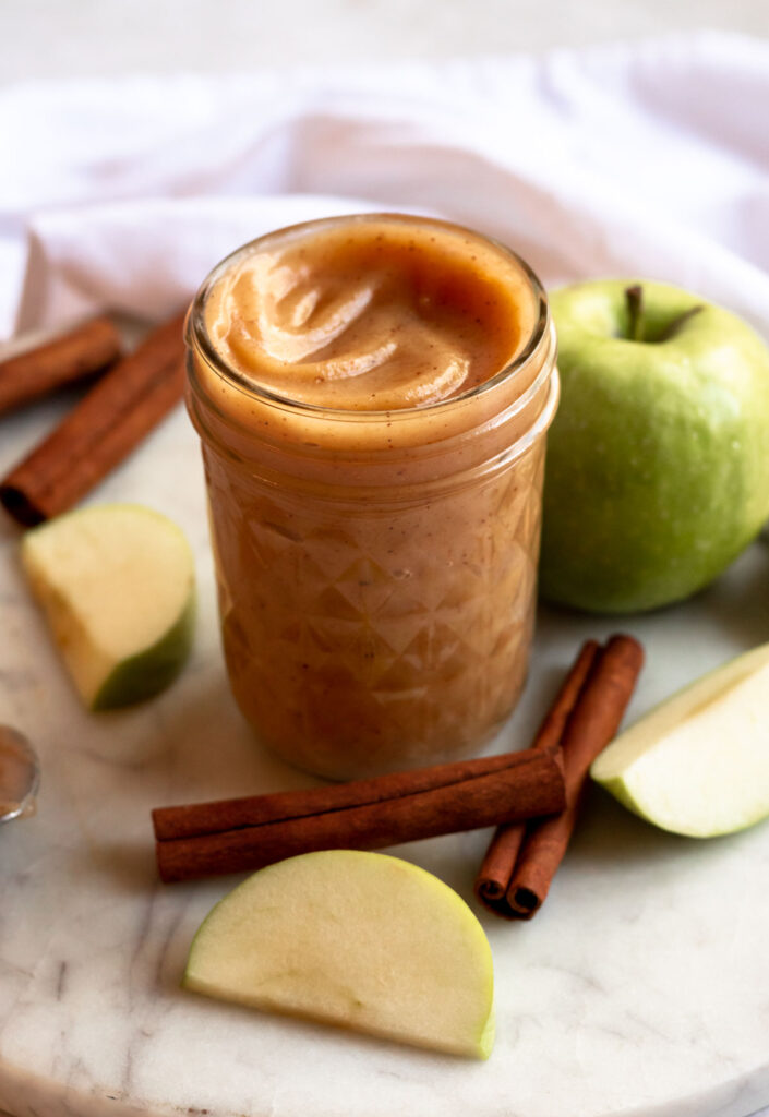 Apple curd in a jar with a spoon in it.