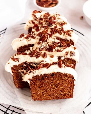 Carrot cake loaf with cream cheese frosting and chopped pecans.
