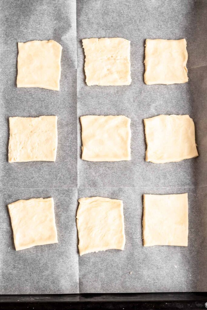 Dough squares on a parchmemt paper lined baking sheet.