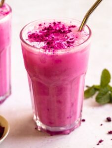 A glass with vibrant pink starbucks dragon drink with a metal straw.