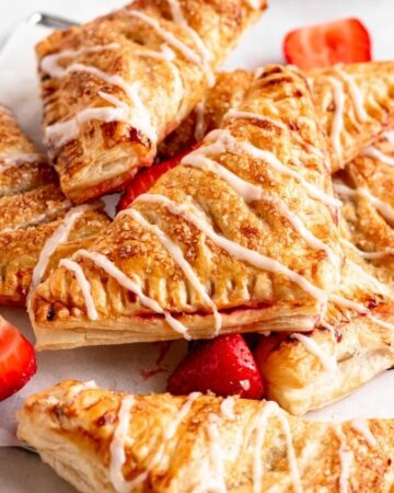 Stack of strawberry turnovers with glaze on top.
