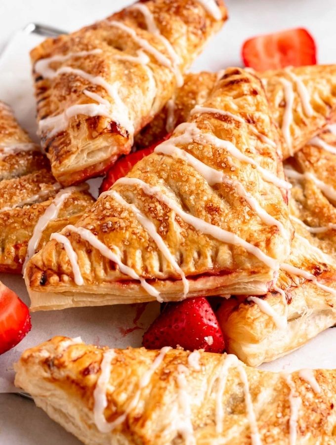 Stack of strawberry turnovers with glaze on top.