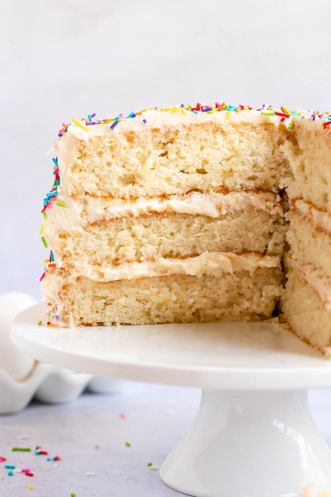 3 layer vanilla cake on a white cake platter.