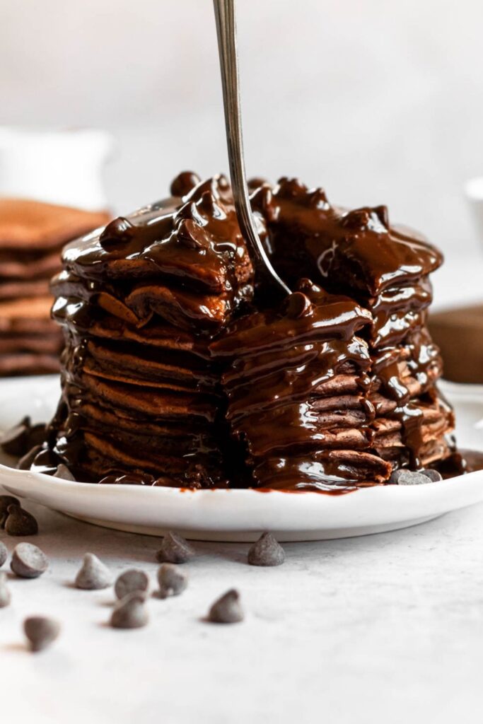 Fork inserted into a stack of double chocolate pancakes.