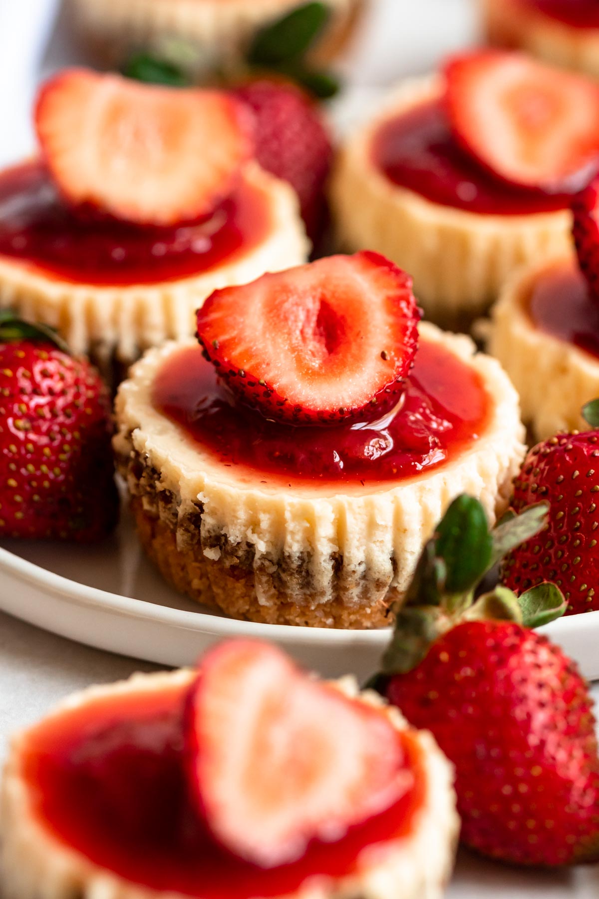 Mini strawberry cheesecakes on a plate.
