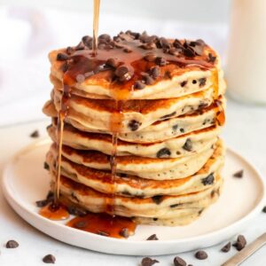 Maple syrup poured on chocolate chip pancakes.