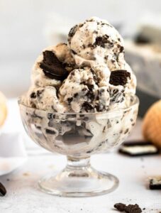 Pile of cookies and cream ice cream in a glass bowl.