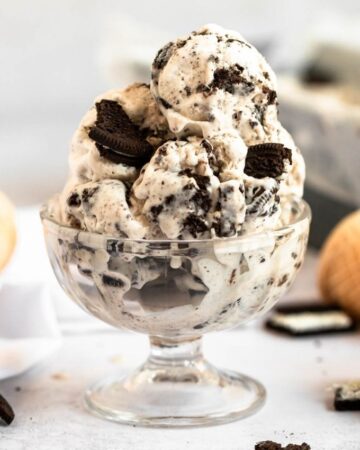 Pile of cookies and cream ice cream in a glass bowl.