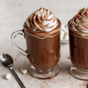 Two cups of french hot chocolate with whipped cream on top.