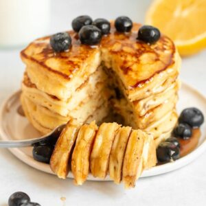 Stack of lemon ricotta pancakes with a bite missing.