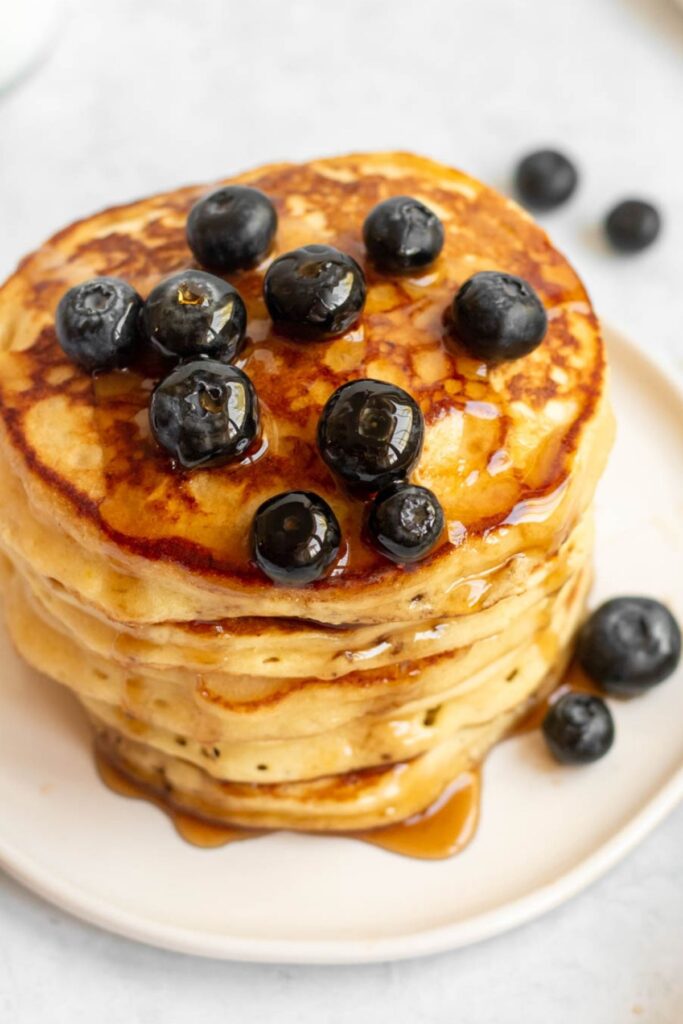 Close up shot of a stack of pancakes on a white plate.