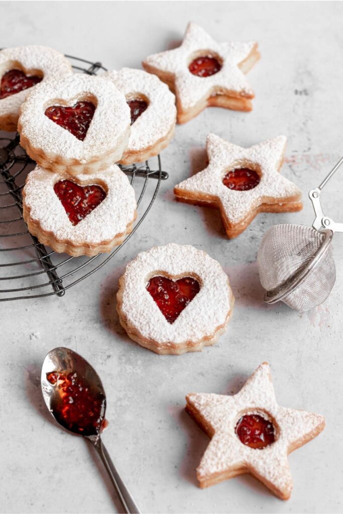 Linzer cookies on a round cooling rack surrounded by more cookies.