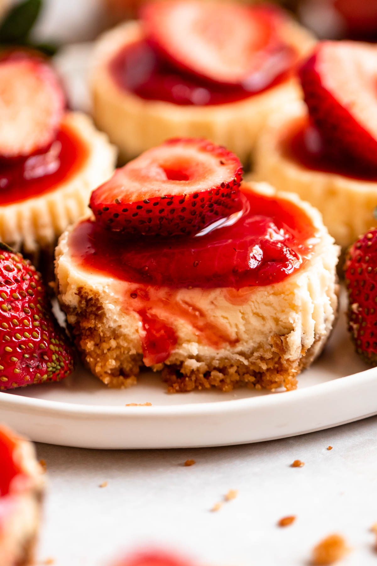 Bite missing from a mini strawberry cheesecake.