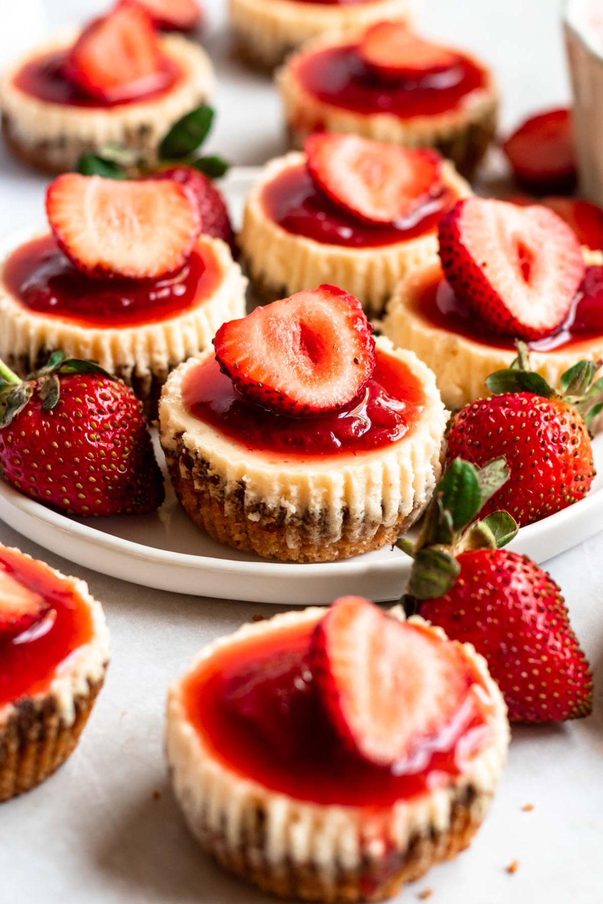 4 miniature strawberry cheesecakes on a plate.