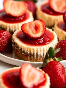 Mini strawberry cheesecakes on a plate.